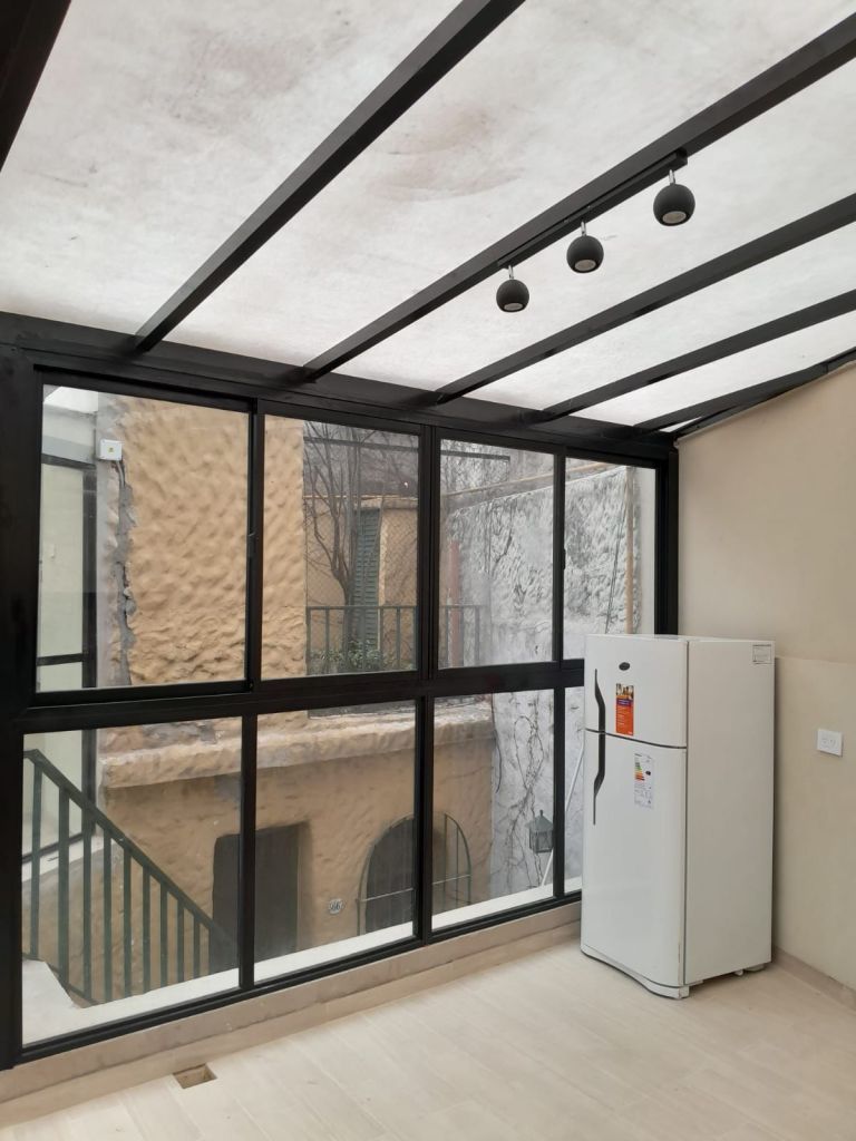 Cerramiento vertical en aluminio negro y techo translucido en poliacrílico anti granizo